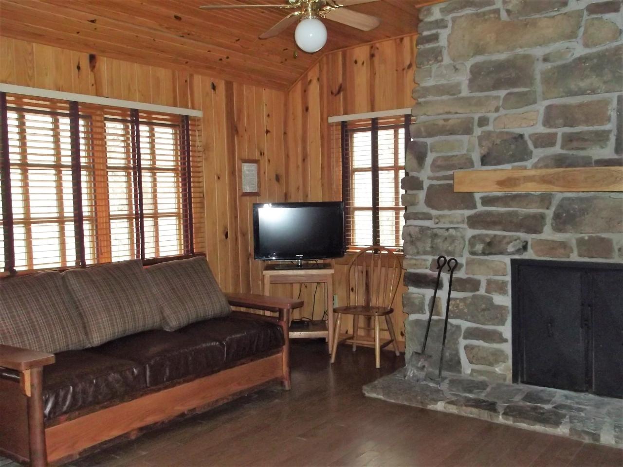 A view of the living area in cabin 10 including a couch, tv and fireplace